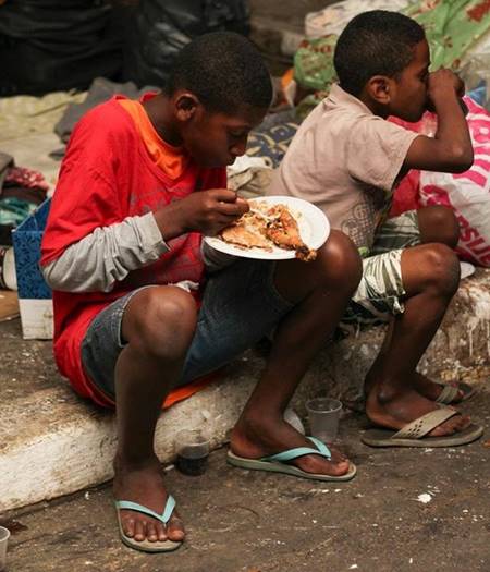 Crianças na calçada, comendo a  ceia de natal