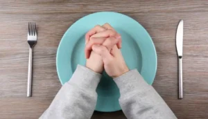 Homem orando sobre o prato representando o jejum - @Reprodução