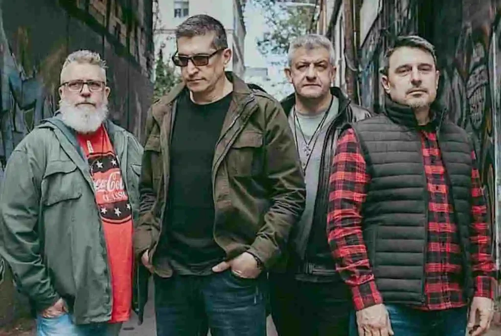 Banda gospel formada por quatro homens adultos posando em rua com grafites ao fundo.