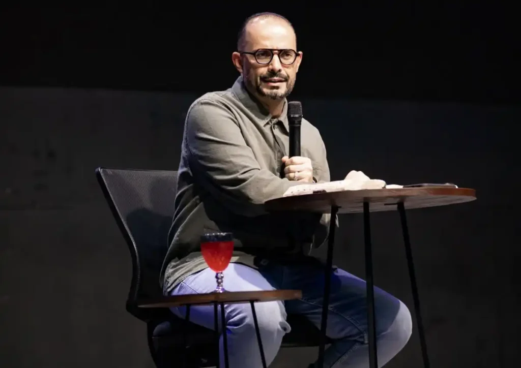 Bispo Adson Belo, líder da Igreja Cidade IMAFE, fala ao microfone durante pregação em palco