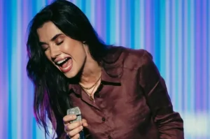 Isadora Pompeo canta ao vivo segurando microfone durante apresentação gospel.