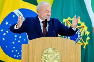 Presidente Luiz Inácio Lula da Silva discursando com os braços abertos no púlpito durante pronunciamento oficial no Palácio do Planalto.