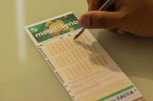 Apostador marcando números em volante da Mega-Sena sobre uma mesa.