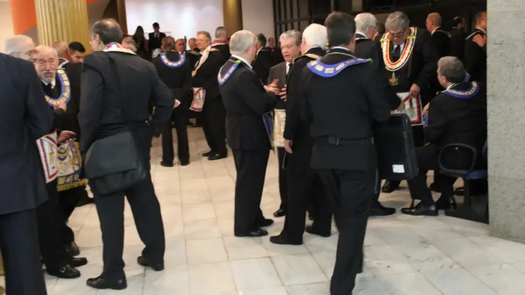 Integrantes da maçonaria reunidos em sessão solene com trajes e insígnias em templo maçônico