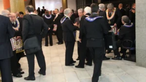 Integrantes da maçonaria reunidos em sessão solene com trajes e insígnias em templo maçônico