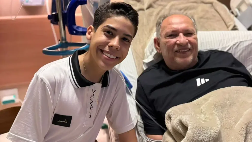 Miguel Oliveira posa sorrindo ao lado de Napoleão Falcão durante visita em hospital