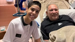 Miguel Oliveira posa sorrindo ao lado de Napoleão Falcão durante visita em hospital