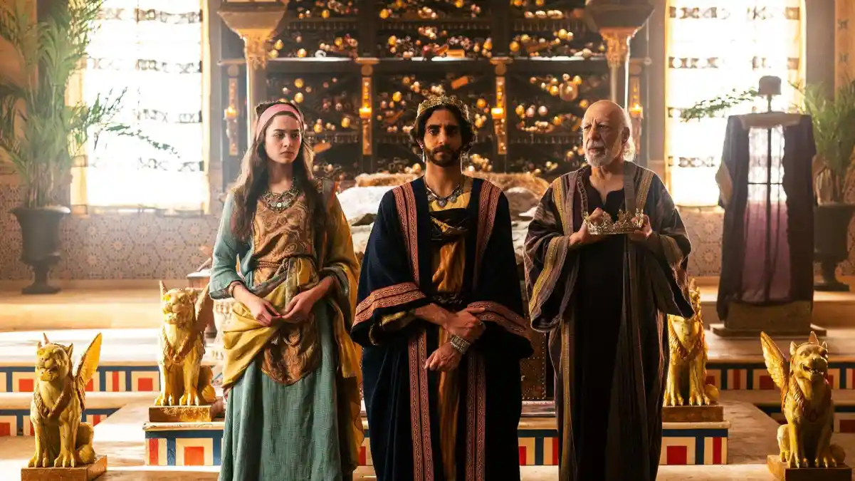 Cena da série The Solomon Saga com três personagens em trajes de época em um palácio decorado com estátuas douradas Cena da série The Solomon Saga com três personagens em trajes de época em um palácio decorado com estátuas douradas