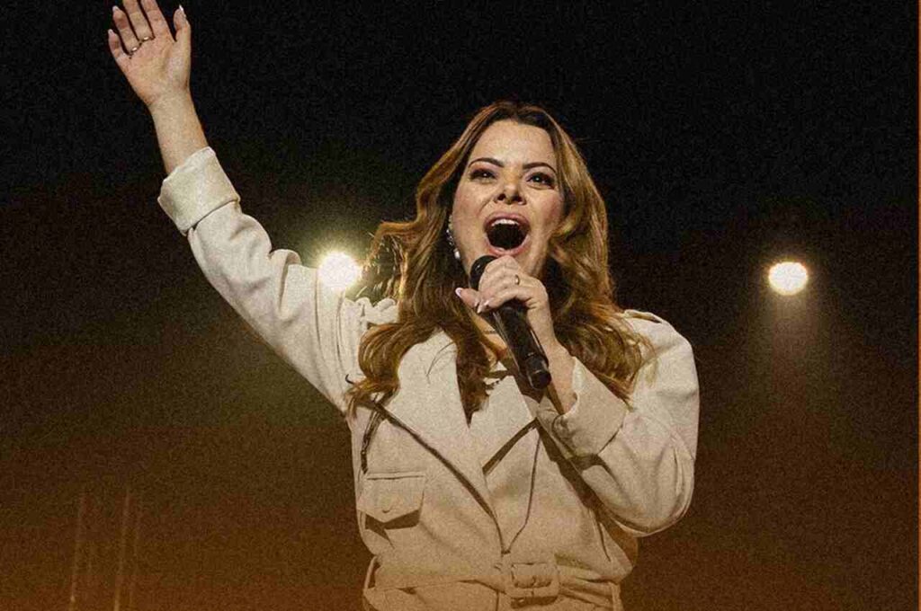 Cantora gospel Ana Paula Valadão cantando com a mão levantada durante momento de louvor em evento cristão.