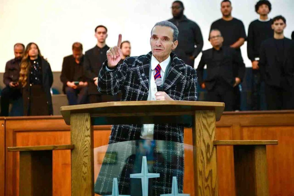Bispo Samuel Ferreira pregando com dedo em riste no púlpito da Assembleia de Deus Ministério do Belém durante culto com coral ao fundo.