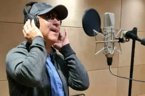 Alex Gonzaga grava vocal em estúdio usando fones de ouvido e microfone profissional.