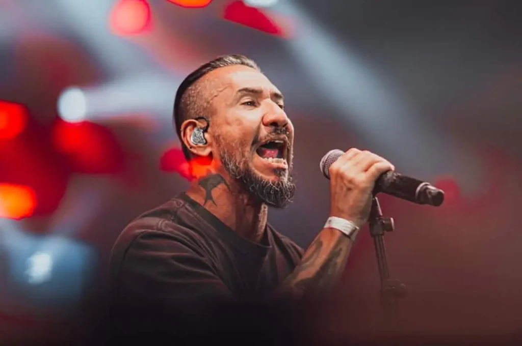 Cantor Rodolfo Abrantes cantando com intensidade no palco durante apresentação de música cristã, segurando o microfone sob iluminação vermelha.