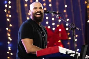 Cantor Sérgio Saas cantando ao teclado durante apresentação ao vivo em evento musical.