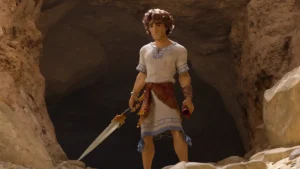 Personagem em túnica segura espada na entrada de uma caverna em cena do filme “Davi nasce um rei”