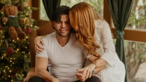 profeta Roberto Ruiz sentado em poltrona é abraçado pela esposa Viviane Ruiz em ambiente interno com decoração ao fundo