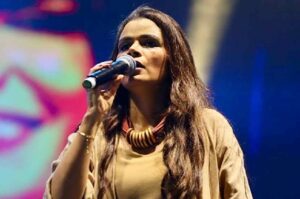 Cantora Damares cantando ao vivo com microfone em show gospel, em apresentação marcada por expressão de emoção e louvor.