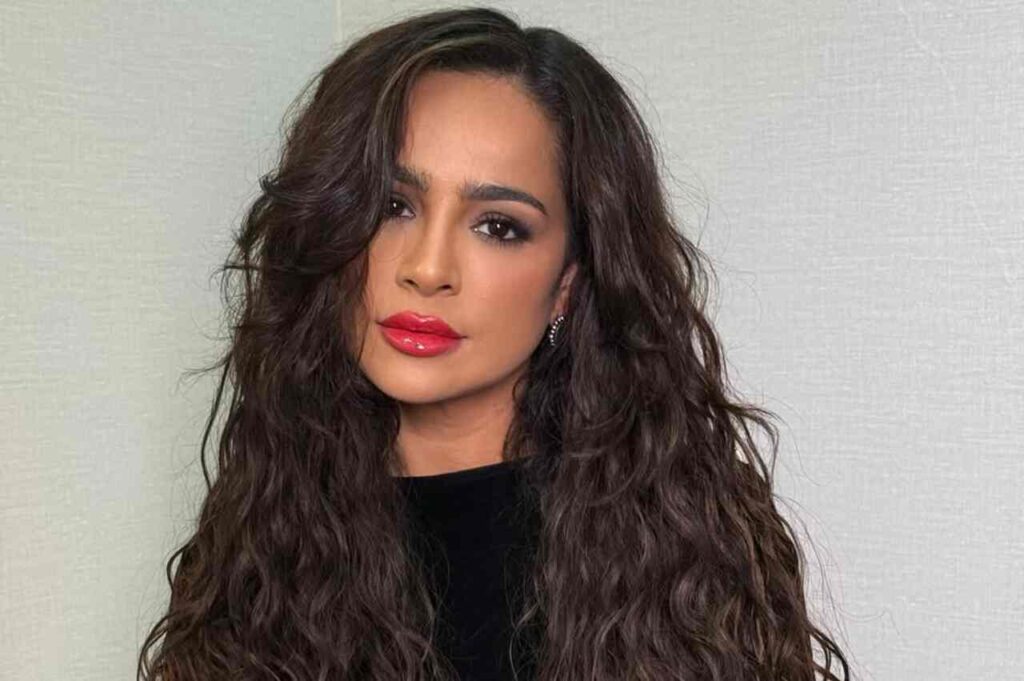 Cantora Daniela Araújo em retrato profissional, com cabelo longo ondulado, maquiagem discreta e batom vermelho, olhando para a câmera.