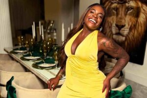 Jojo Todynho sorrindo e posando com vestido amarelo em ambiente sofisticado durante ensaio fotográfico.