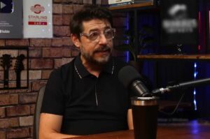 Pastor Emerson Pinheiro sentado em estúdio de podcast, usando óculos, falando ao microfone