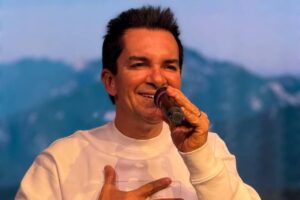 Régis Danese cantando com expressão de alegria e mão no peito durante apresentação de louvor em evento gospel.