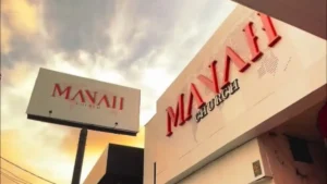 Fachada da Manah Church com letreiro “MANAH CHURCH” em vermelho e placa externa com o nome da igreja ao lado