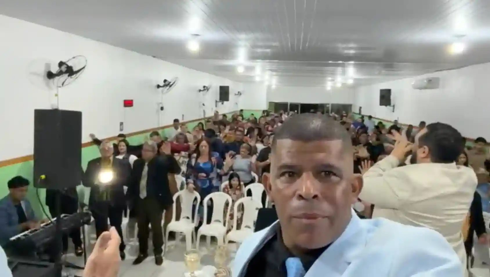Pastor André Rodrigues grava vídeo durante o Aviva Manaus em igreja lotada com fiéis ao fundo