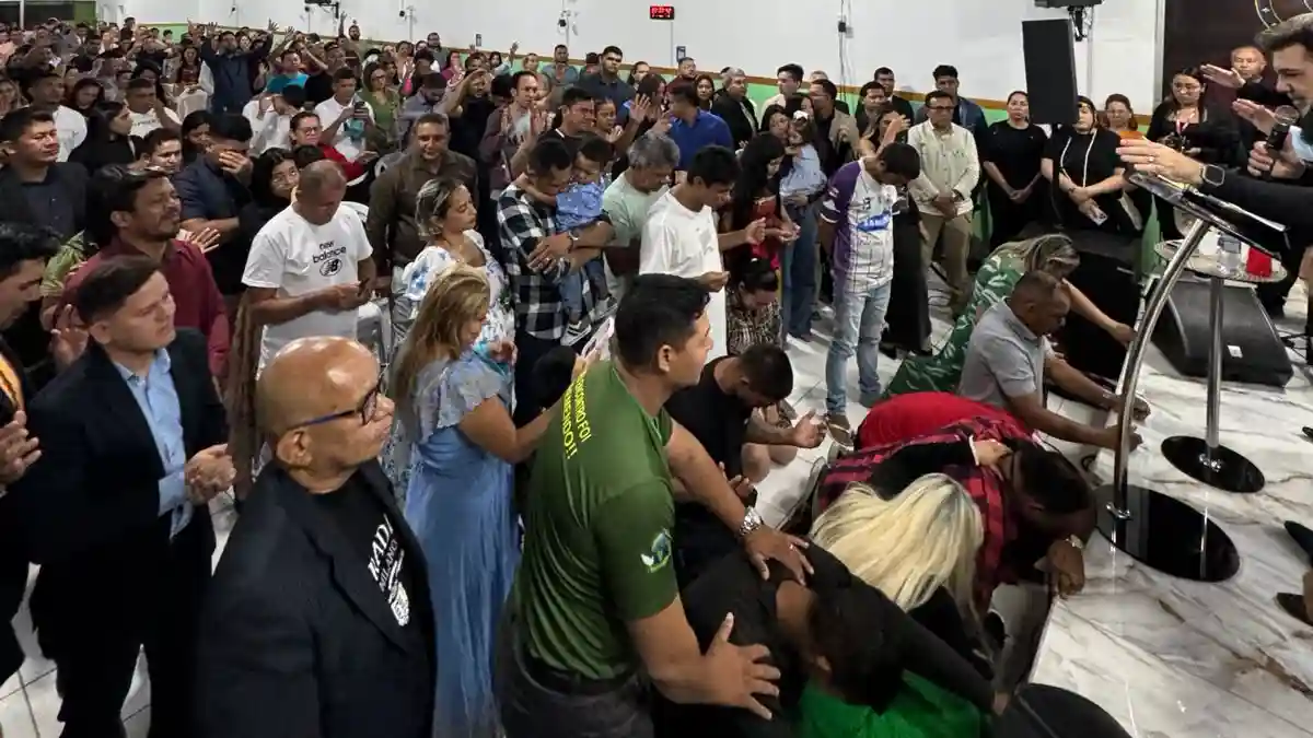 Pastor Marcos Feliciano ora por fiéis no final do culto em igreja lotada com pessoas ajoelhadas perto do altar