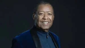 Ron Kenoly sorri em retrato de estúdio com blazer azul e fundo escuro