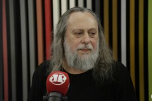 Pastor Caio Fábio durante entrevista em estúdio com microfone enquanto participa de programa.