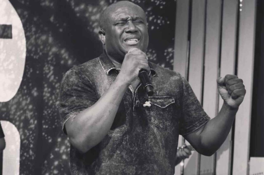 Cantor gospel Irmão Lázaro cantando ao microfone com expressão intensa durante apresentação