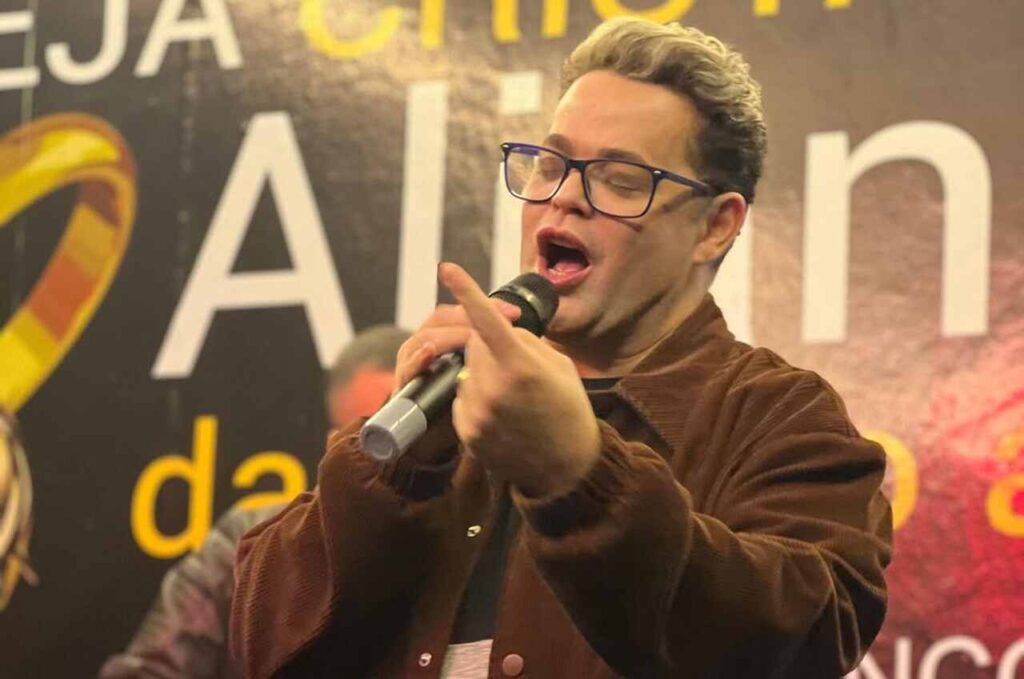 Cantor Robinson Monteiro cantando ao microfone durante apresentação