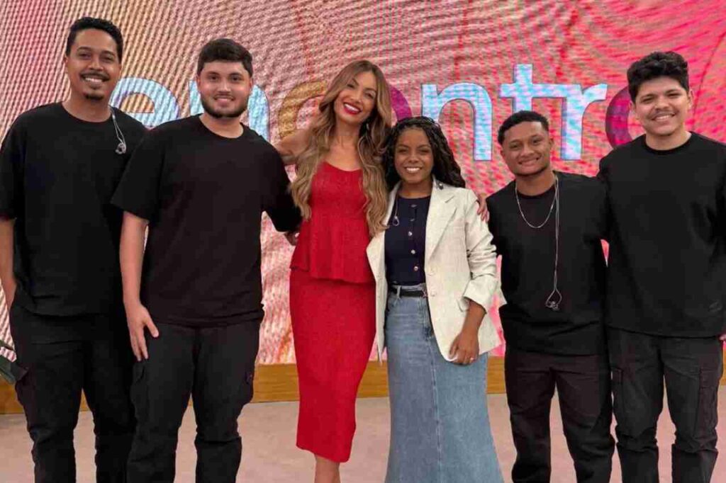Cantora gospel Kemilly Santos posa com banda durante participação em programa da TV Globo.