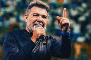 Pastor Marco Feliciano pregando ao microfone com gesto de ênfase durante evento.