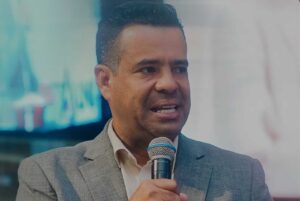Pastor Moisés Leopoldino pregando ao microfone durante culto em igreja enquanto ministra mensagem.