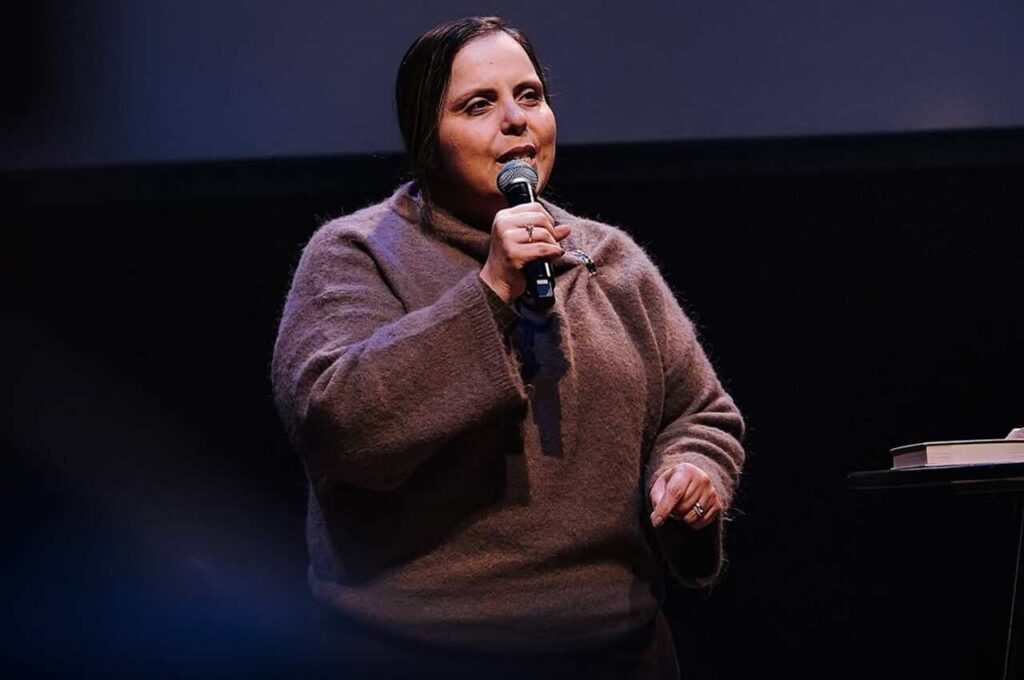 Pastora Helena Raquel ministrando ao microfone durante pregação em evento cristão.
