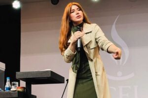 Pregadora Leandra Nascimento ministra mensagem segurando microfone e