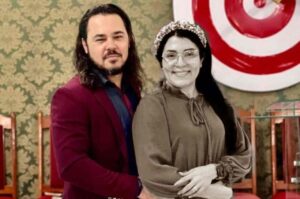 Cantora Sarah Freitas ao lado de Ederlan em foto de casal em ambiente interno.