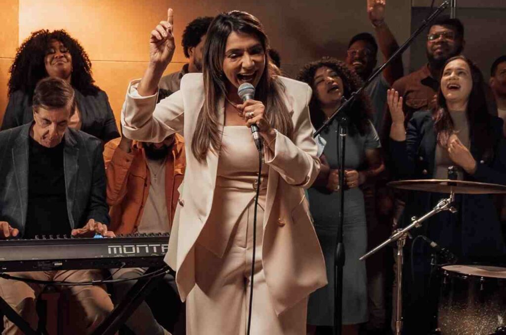 Cantora gospel Soraya Moraes ministrando louvor com banda e backing vocals durante apresentação.