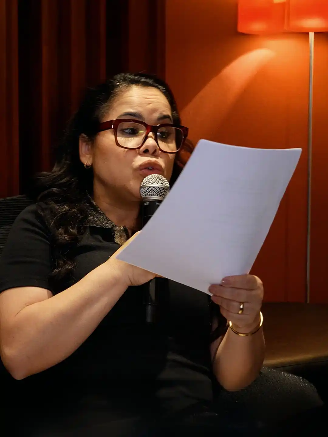 Cassiane lê um papel e fala ao microfone durante gravação em estúdio