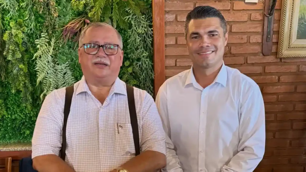 Pastor Orisvaldo Nunes e o pregador Deywison Pontes posam lado a lado em ambiente interno com parede de tijolos e jardim vertical