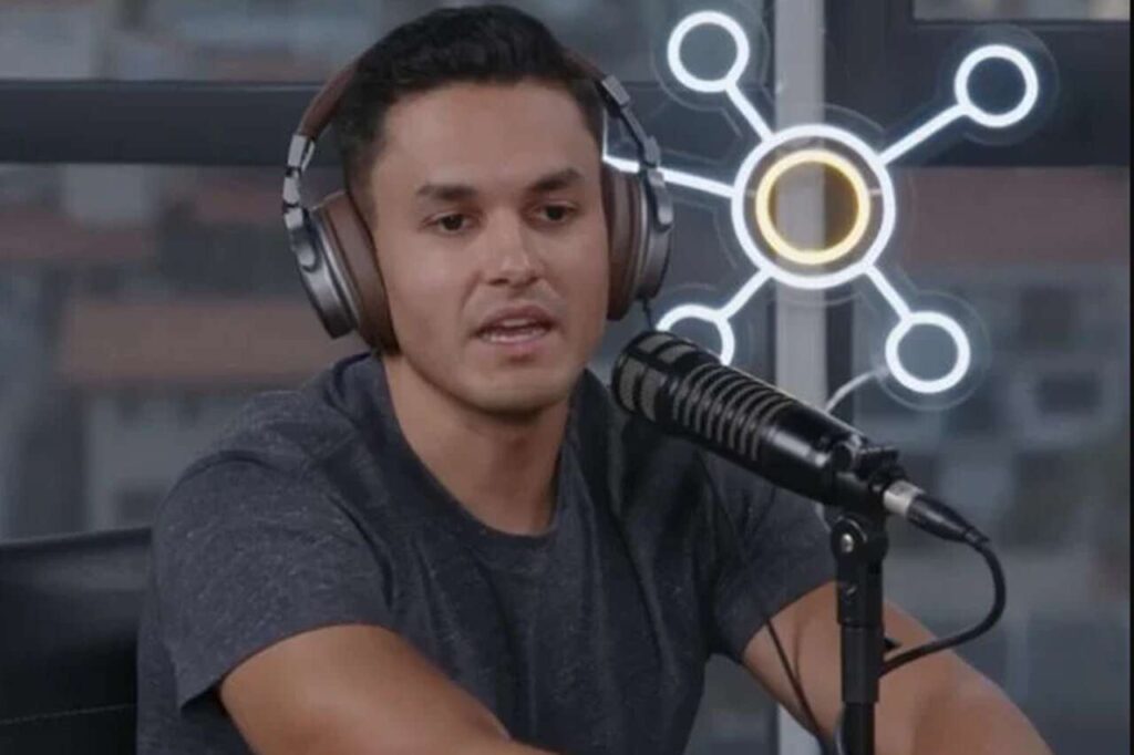 David Miranda Neto participando de podcast, usando fones de ouvido e falando ao microfone.