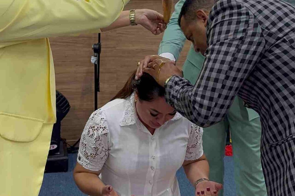 Luiana Trovão recebe oração com imposição de mãos durante momento em igreja.