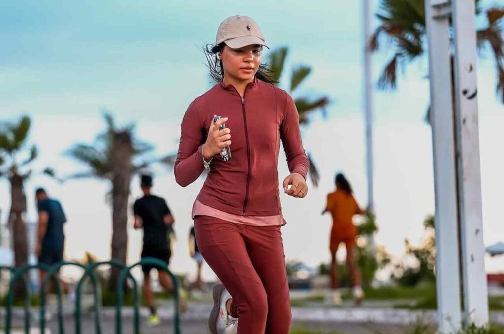 Cantora gospel Maria Marçal praticando corrida ao ar livre, usando roupa esportiva.