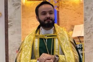 Padre Caio Queiroz durante celebração religiosa em altar, vestindo paramentos litúrgicos.