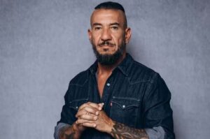 Rodolfo Abrantes em retrato posado, com mãos unidas e expressão séria.