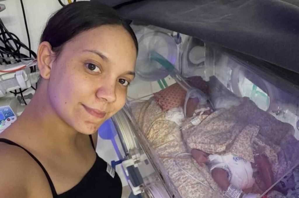 Vitória Souza registra momento ao lado do filho recém-nascido em incubadora hospitalar.