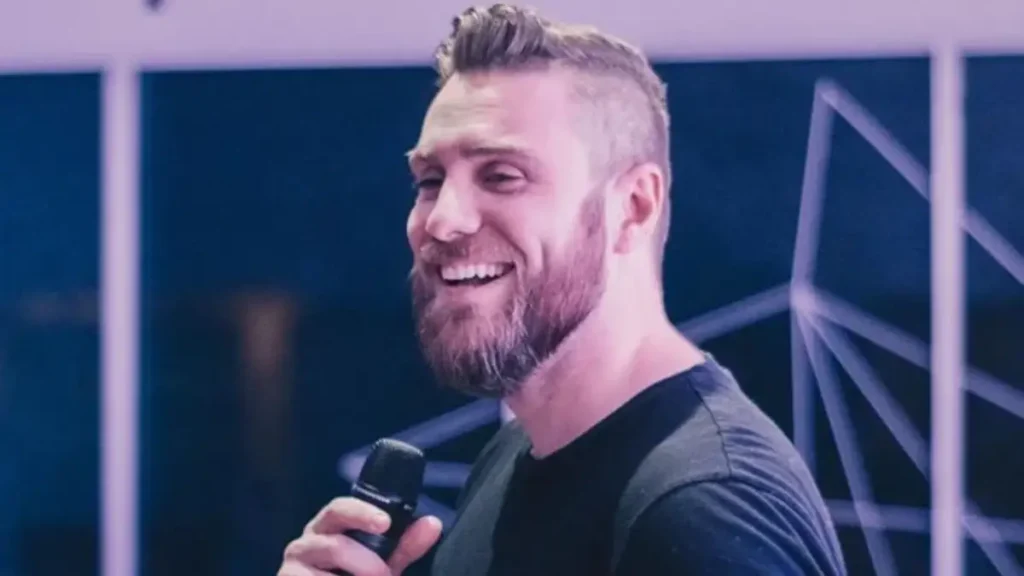 Pastor André Fernandes fala ao microfone durante evento em ambiente interno