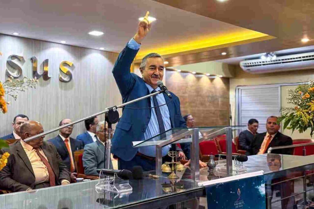 Cantor Ivonaldo Albuquerque prega em púlpito de igreja enquanto levanta uma das mãos durante culto.