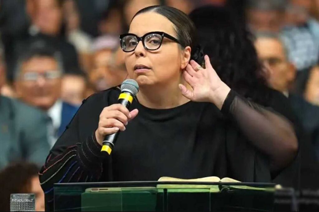 Helena Raquel segurando microfone durante pregação em igreja diante de fiéis.