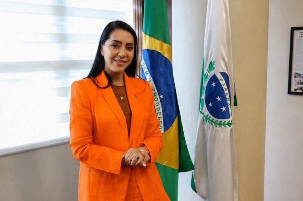 Mara Lima posa em gabinete ao lado das bandeiras do Brasil e do Paraná.